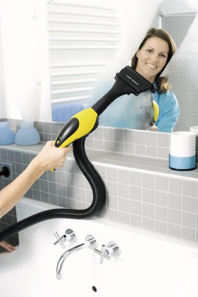Женщина чистит зеркало моющим пылесосом